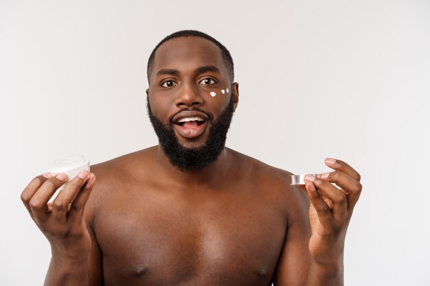 African handsome man applying cream on his face mans skin care concept