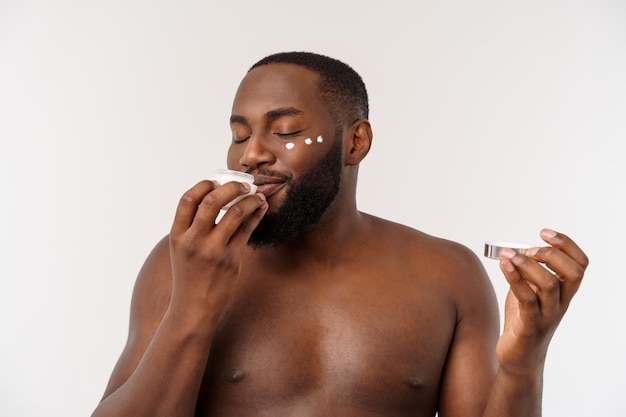 L'uomo africano bello che applica la crema sul suo concetto di cura della pelle dell'uomo del viso