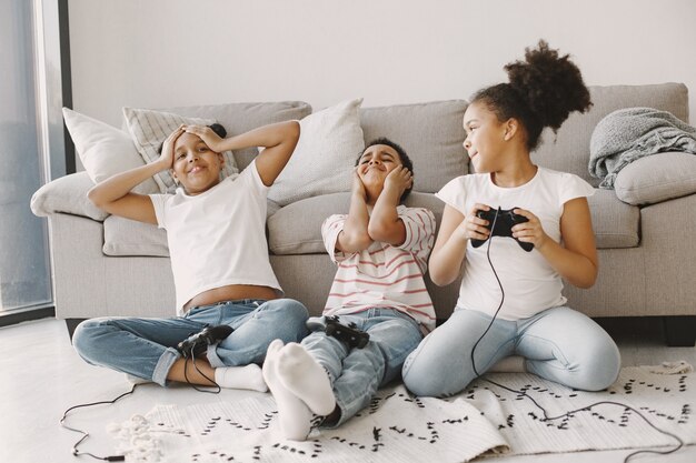 African kids playing video games. Children in light clothes. Controller in hands of children.