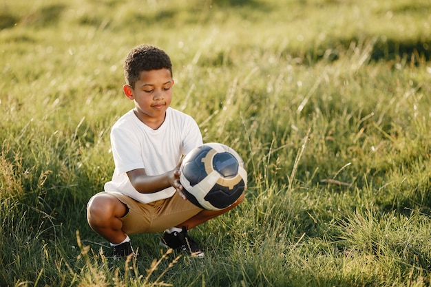 Free photo african little boy. child in a summer park. kid with socer ball.