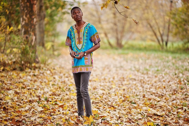 Африканский мужчина в традиционной африканской рубашке в осеннем парке