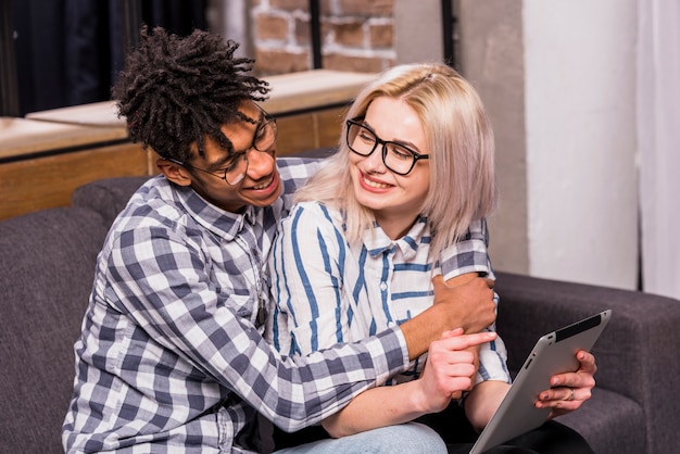 An african man embracing her girlfriend holding digital tablet in hand