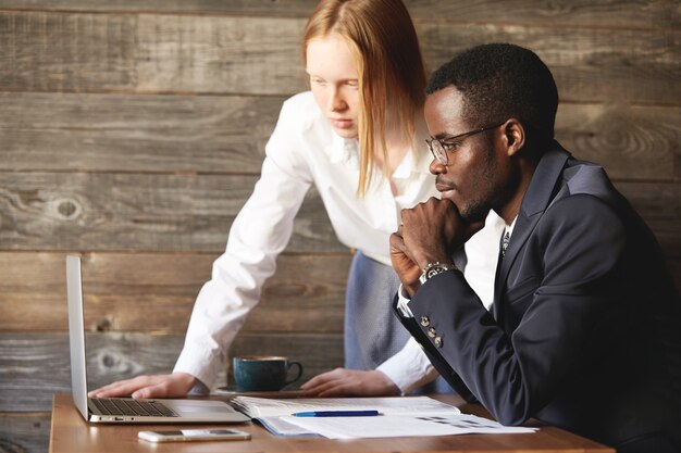 African man in formal suit and Caucasian woman in white shirt videoconferencing and negotiating