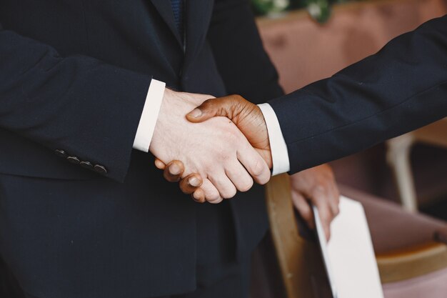 African man. Guy in a black suit. Mixed people shake hands.