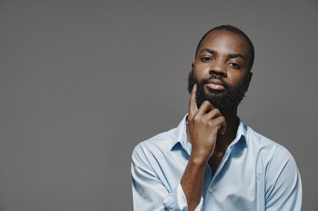 African man in a studio. White wall.  Man in a blue shirt.