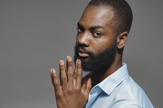 African man in a studio. White wall.  Man in a blue shirt.