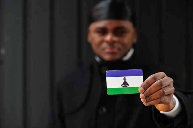 African man wear black durag hold Lesotho flag at hand isolated dark background