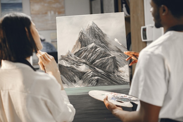 African man and a woman in painting class drawing on an easel.