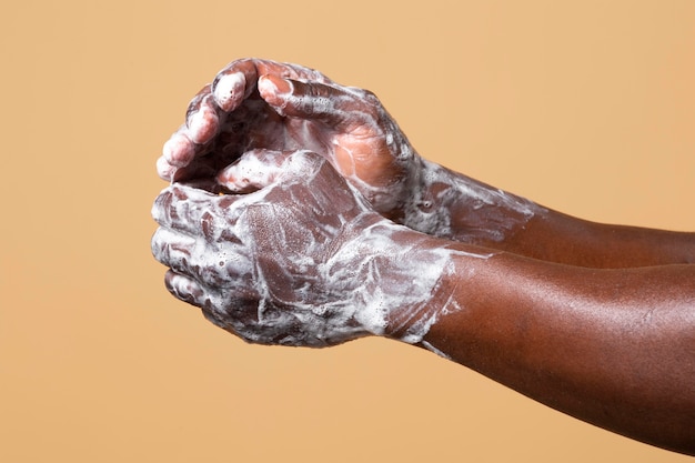 African person washing hands with soap isolated on orange