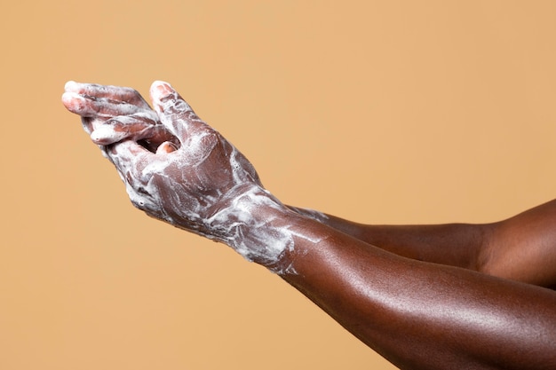 Foto gratuita persona africana che si lava le mani con il sapone isolato sull'arancia