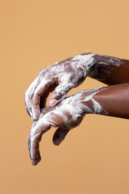 African person washing hands with soap isolated on orange