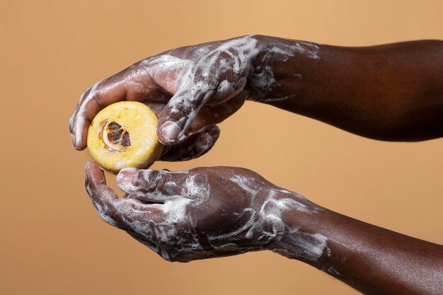 オレンジ色に分離された石鹸で手を洗うアフリカ人