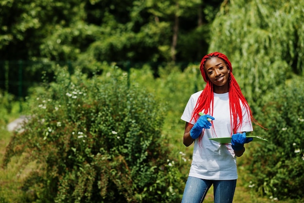 African red haired volunteer woman with clipboard in park Africa volunteering charity people and ecology concept
