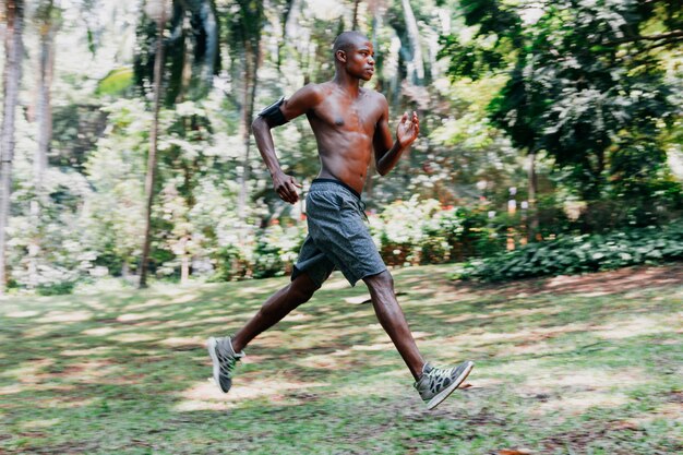 An african shirtless athlete young man running in the park