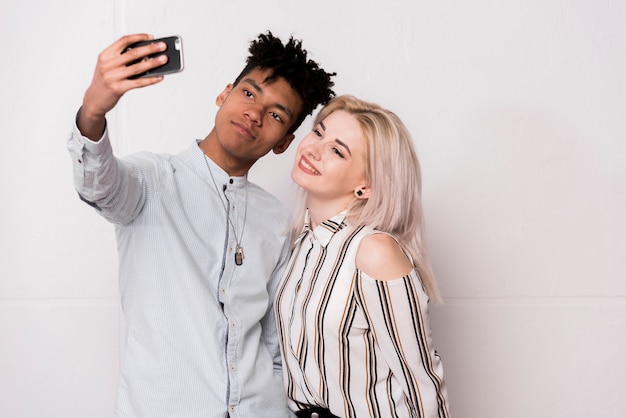 An african teenage boy taking selfie with her girlfriend on mobile phone