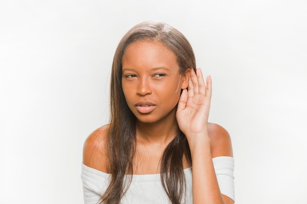 African teenage girl trying to hear on white backdrop