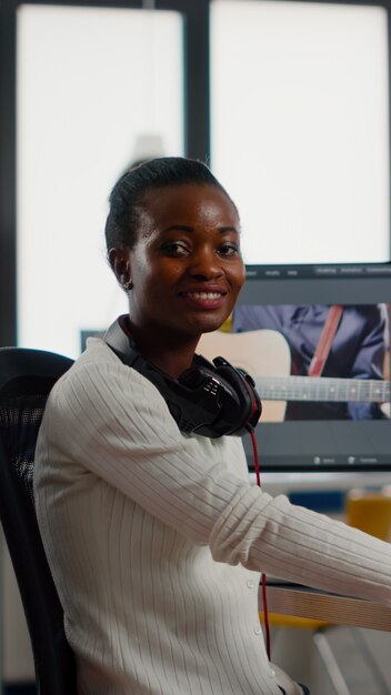 후반 제작 소프트웨어 작업에서 카메라 미소 편집 비디오 프로젝트를 보고 있는 아프리카 비디오 편집자