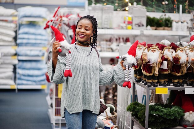 現代の家具店で彼女のアパートのために新年のものを選ぶアフリカの女性クリスマスのテーマの買い物