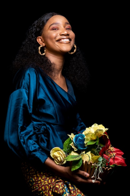 花の花束を保持しているエレガントな服を着たアフリカの女性