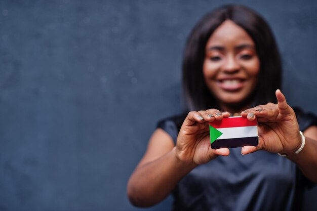 African woman hold small Sudan flag in hands