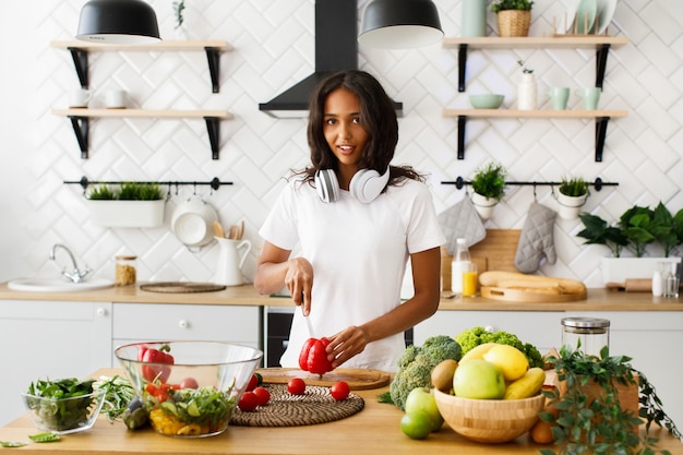 African woman is cutting a red pepper on the kitchen desk