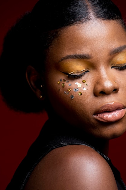 African woman in leather vest with shiny confetti on her cheeks