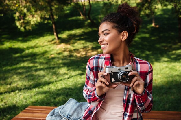 Африканский фотограф женщины сидя outdoors в парке.