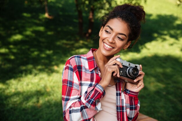 公園の屋外に座っているアフリカの女性写真家。