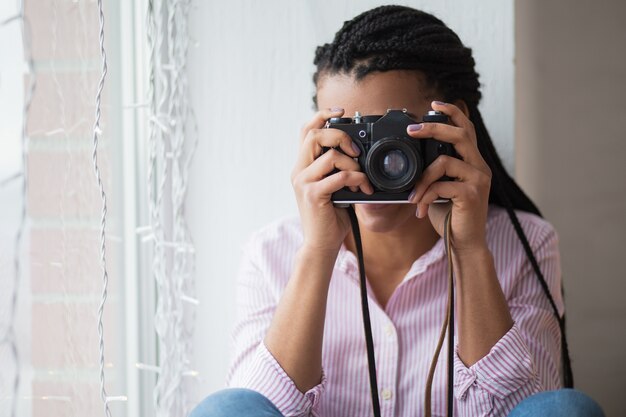 African woman photographing at home