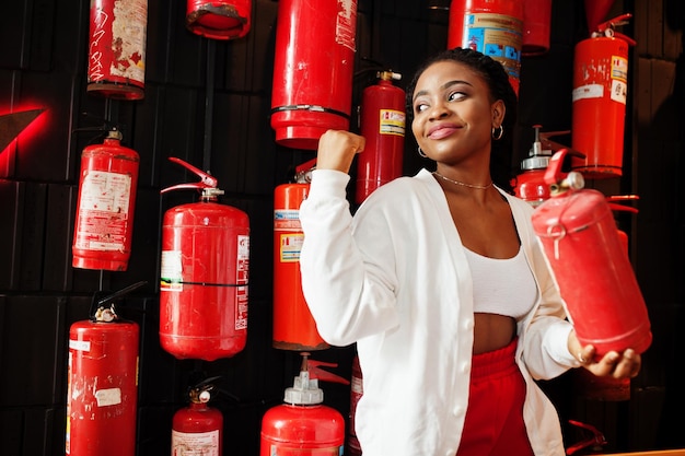 Free photo african woman posed against wall with old extinguisher