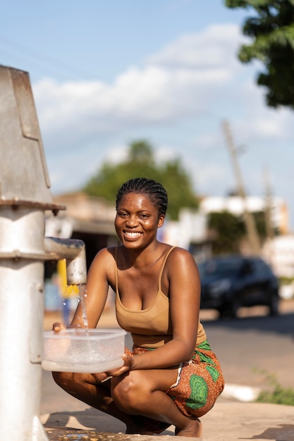 Foto gratuita donna africana che versa acqua in un recipiente