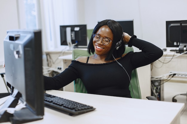 African woman sitting in computer science class. Lady with glasses. Female student sitting at the computer.