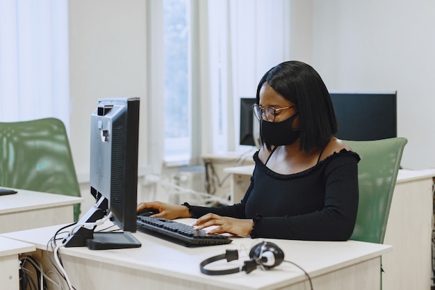 African woman sitting in computer science class. Lady with glasses. Female student sitting at the computer.