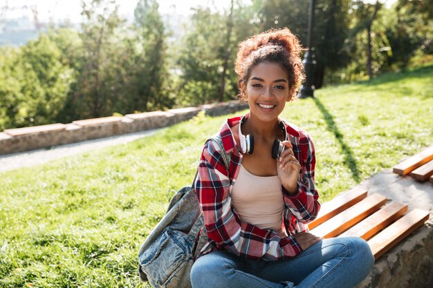 African woman sitting outdoors in park.