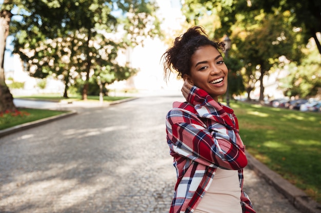 African woman walking outdoors in park. Looking camera.