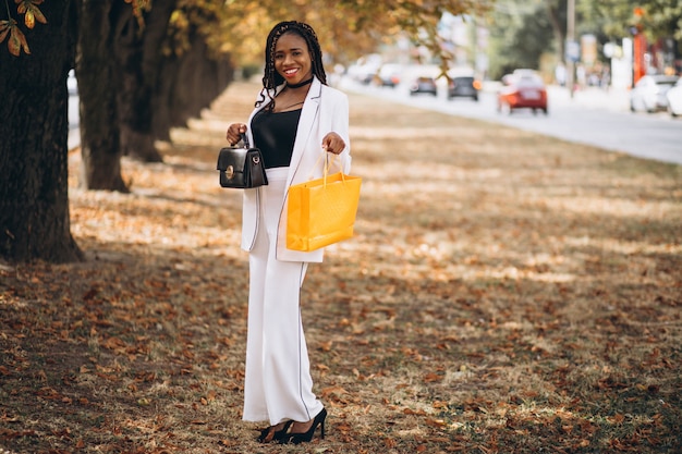 African woman with yellow shopping bags in park