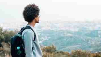 Free photo an african young male hiker with his backpack looking at view