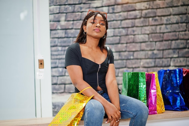 Афроамериканка сидит с цветными сумками в торговом центре торгового центра