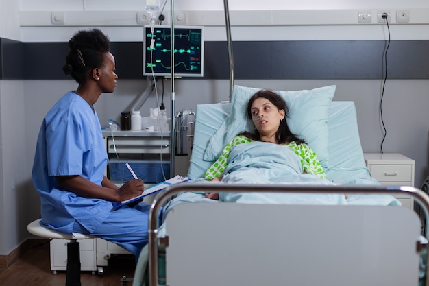 Afro american asisstant monitoring sick woman discussing sickness symptom