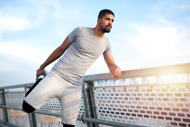 Free photo afro american athlete stretching his legs before running