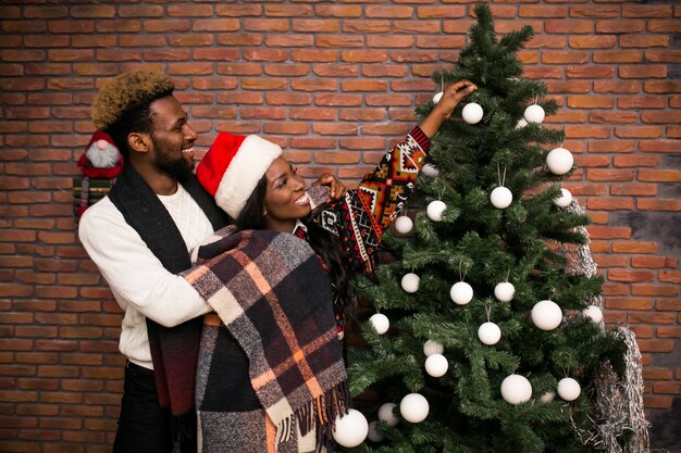 Afro american couple hanging toys on a Christmas tree