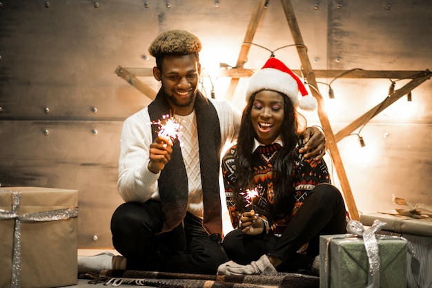 Afro american couple sitting with bengal lights