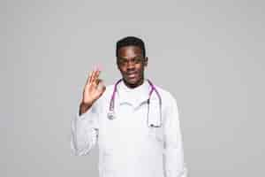 Free photo afro american doctor with stethoscope showing okay gesture isolated on gray background