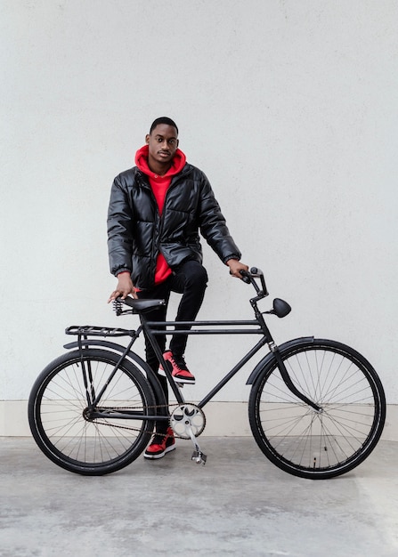 Афро-американский мужчина держит велосипед перед ним