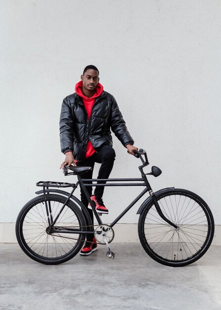 Afro-american man holding his bicycle in front of him