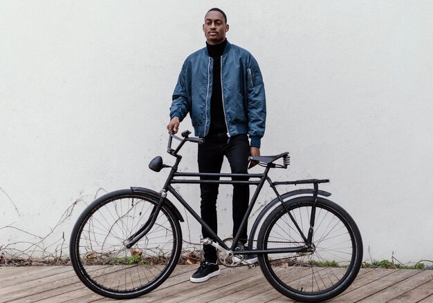 Afro-american man holding his bicycle in front of him