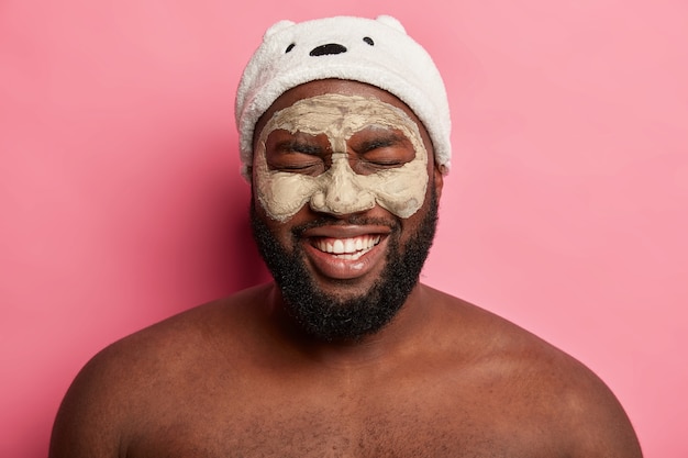 Uomo afroamericano con maschera all'argilla, esprime emozioni positive isolate