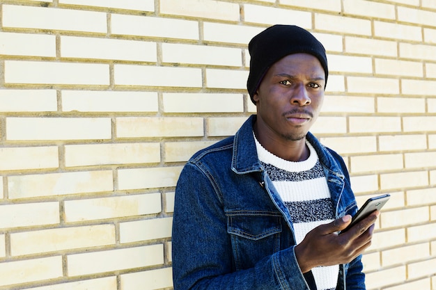 Afro american man with smartphone in front of wall