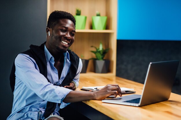 Afro-American student working from home using laptop at kitchen.