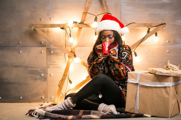 Afro american woman drinking coffee on a Christmas eve